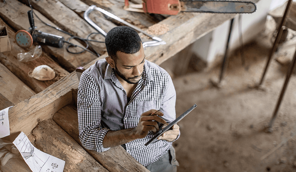 Man in a woodworking shop looking at a tablet.