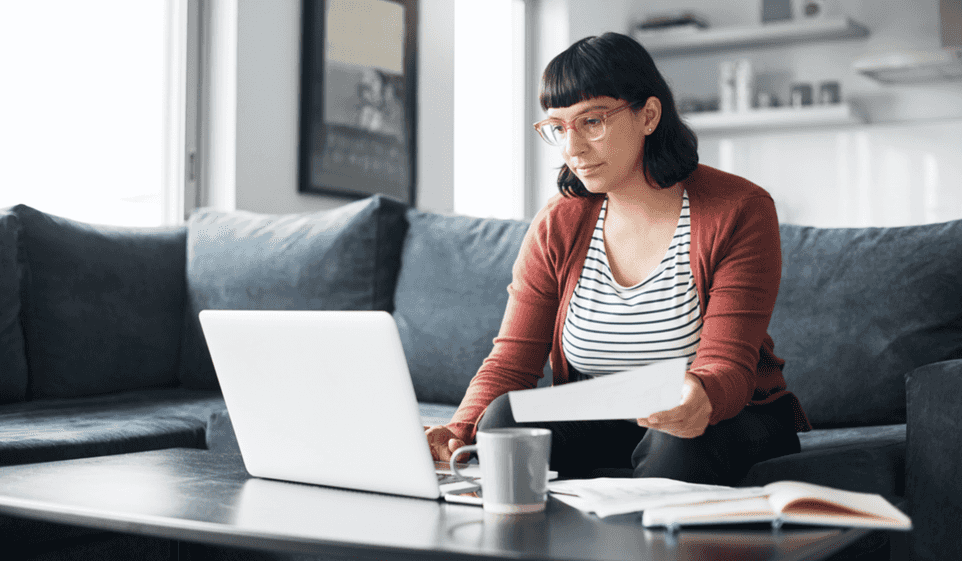 Woman sitting on coucj looking at her laptop on a coffee table