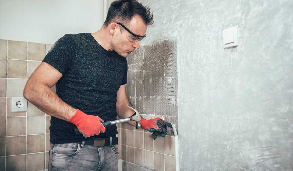 Even if you’re working for yourself, you still need self-employed insurance, like this handyman working on bathroom tile.