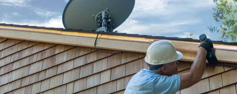 TV satellite installer working on slanted roof