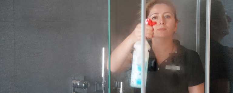 A woman cleaning a shower door