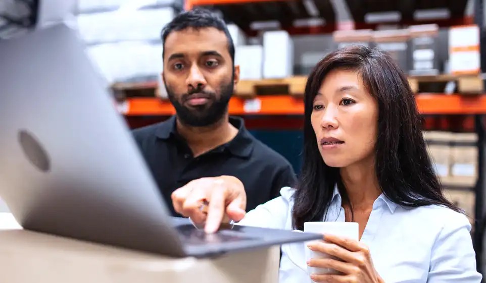 Two workers researching monopolistic workers comp states on the laptop
