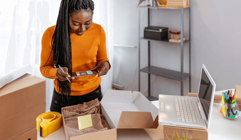 A woman taking a photo with a smartphone of a product in a box