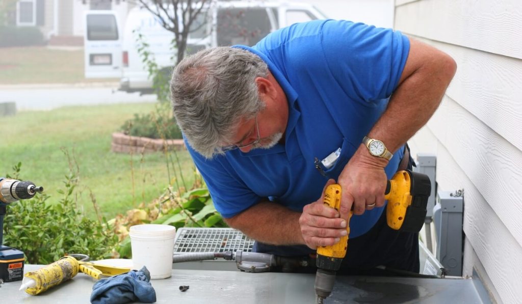 A contractor who owns a contractor’s license in Illinois is using a drill.