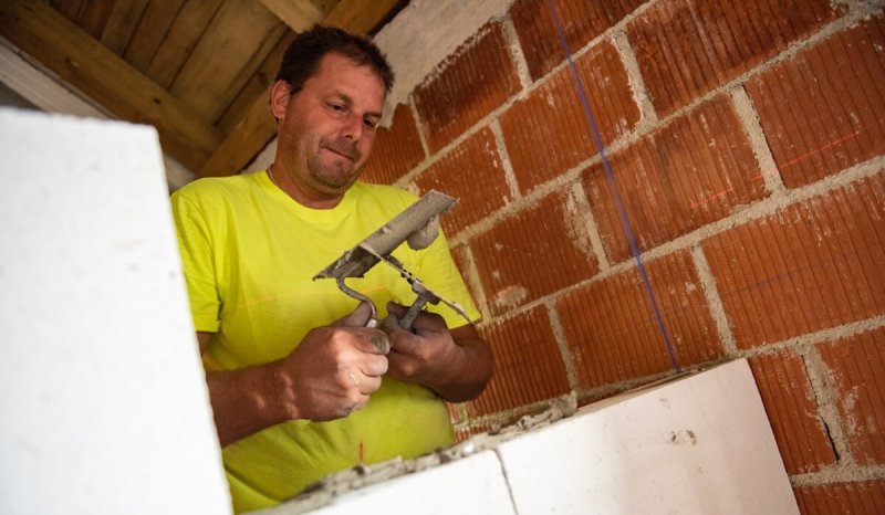 A brick layer with a North Carolina business license works on a wall.