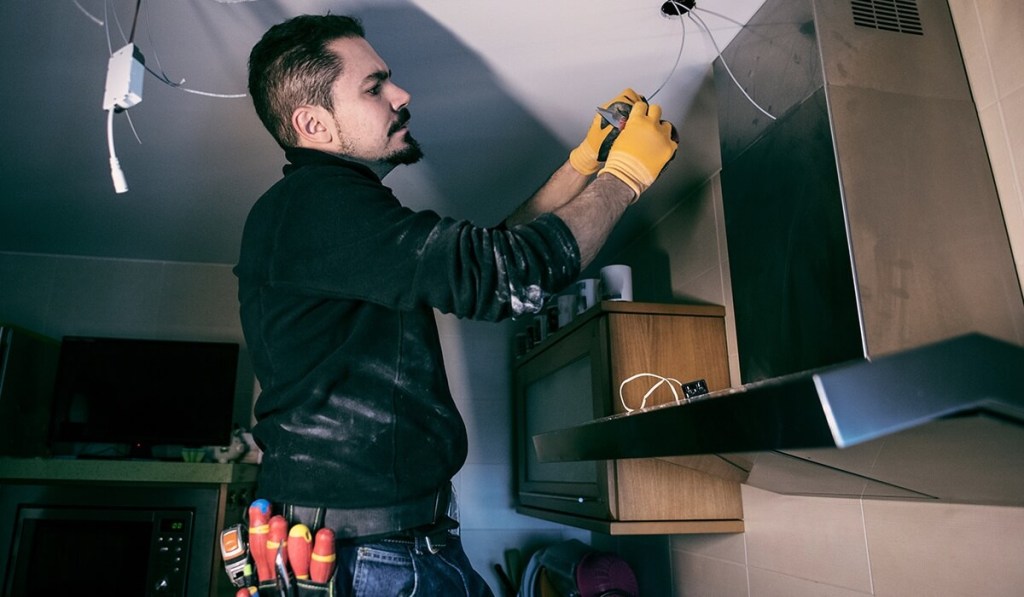 Getting a Maine contractor license lets you work in clients’ homes, like this contractor installing a kitchen cabinet.