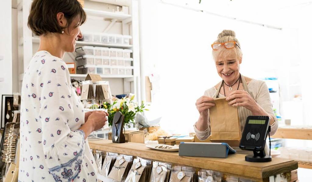 After meeting with a loyal customer, a business owner folds up a small bag of merchandise