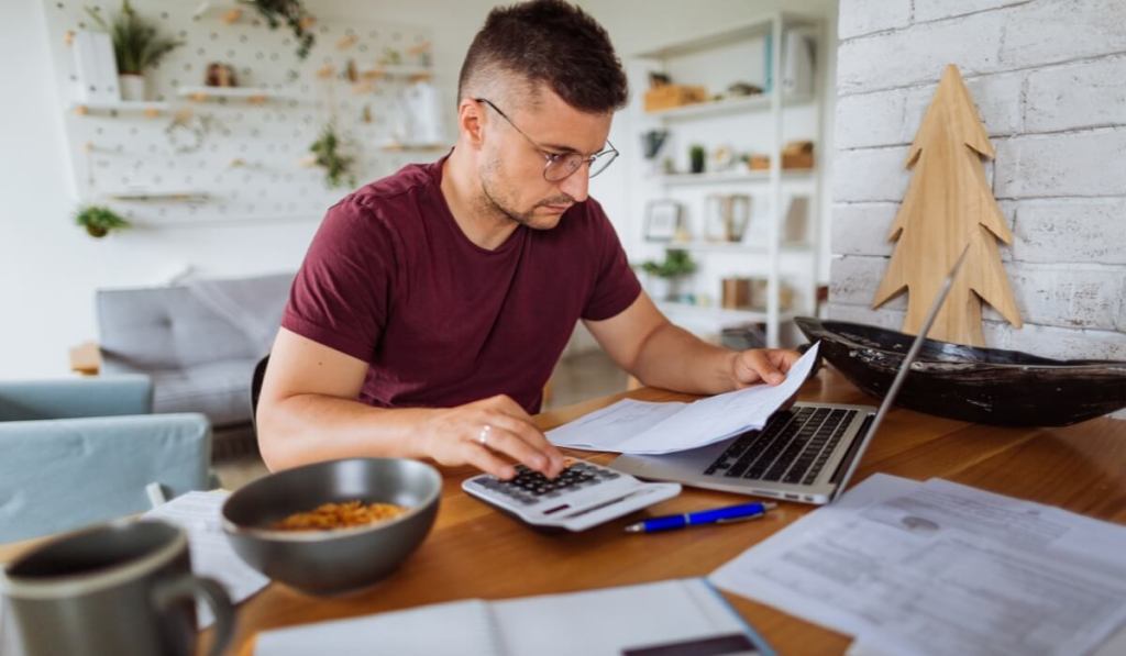 Man sitting at computer with calculator.