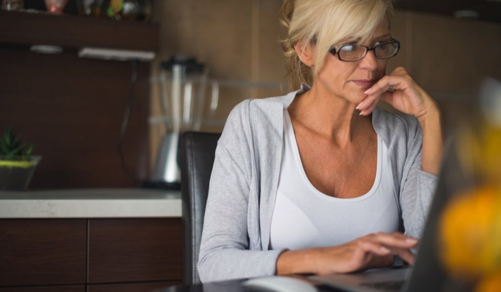 An entrepreneur researches web hosting for her small business website on her laptop.