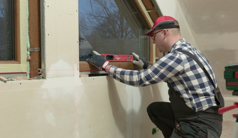 Man with a WA license using a level against a wall.