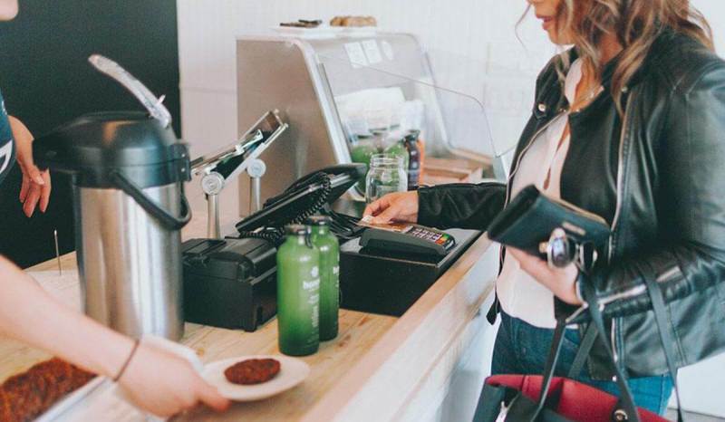 Business woman is using her small business credit card to pay for her lunch at a restaurant