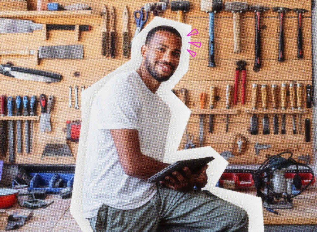 Handyman sitting on a work bench with tools hanging in the background