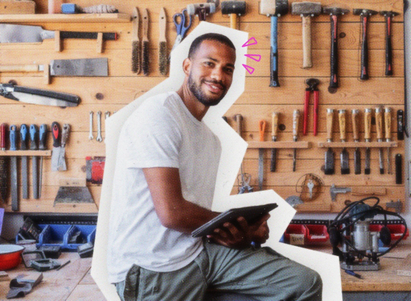 Handyman sitting on a work bench with tools hanging in the background