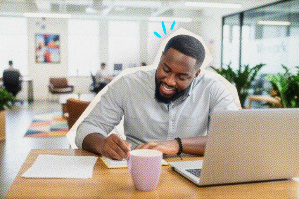 solopreneur writing notes in a notebook while smiling in front of a laptop