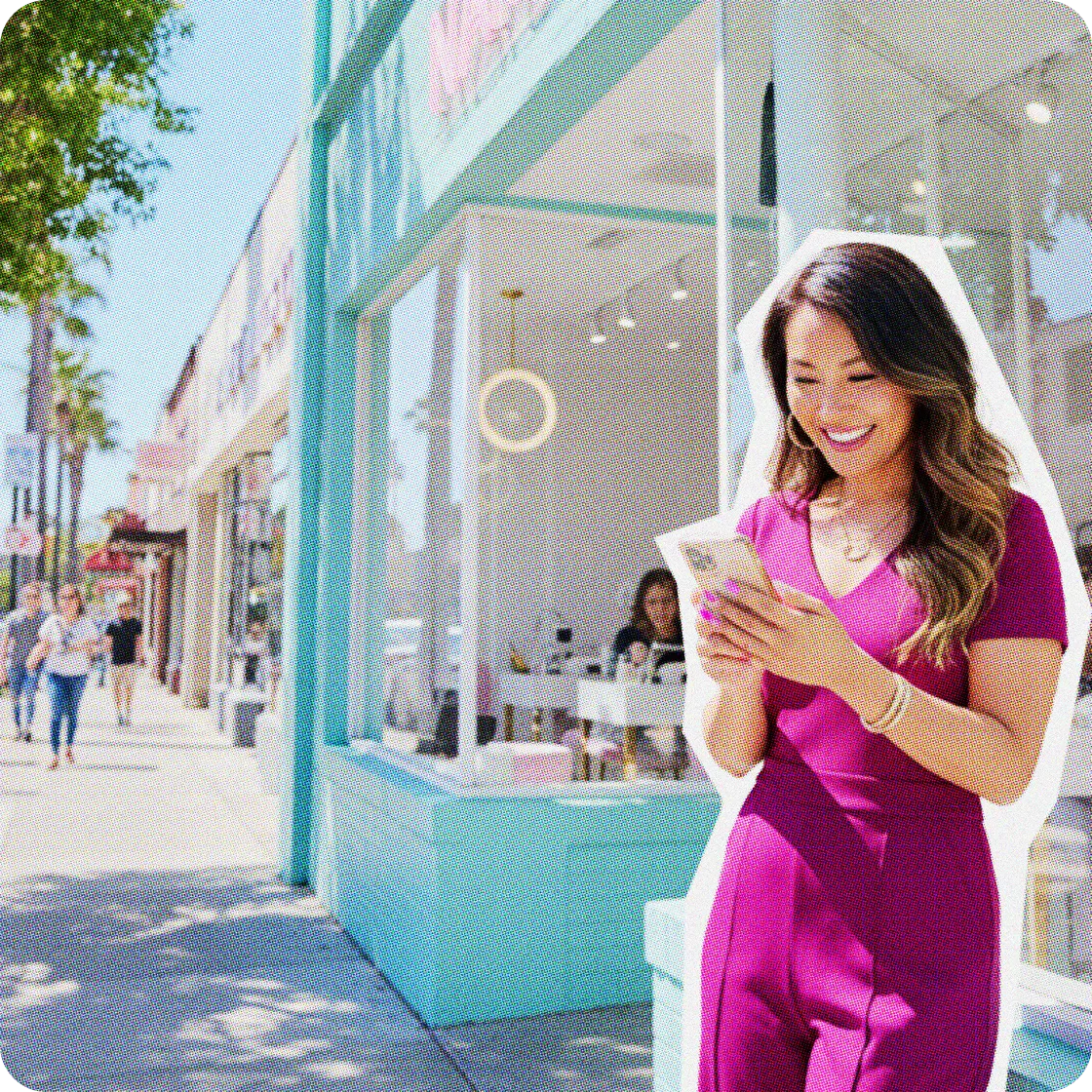 A woman in pink scrubs using her phone outside her business.