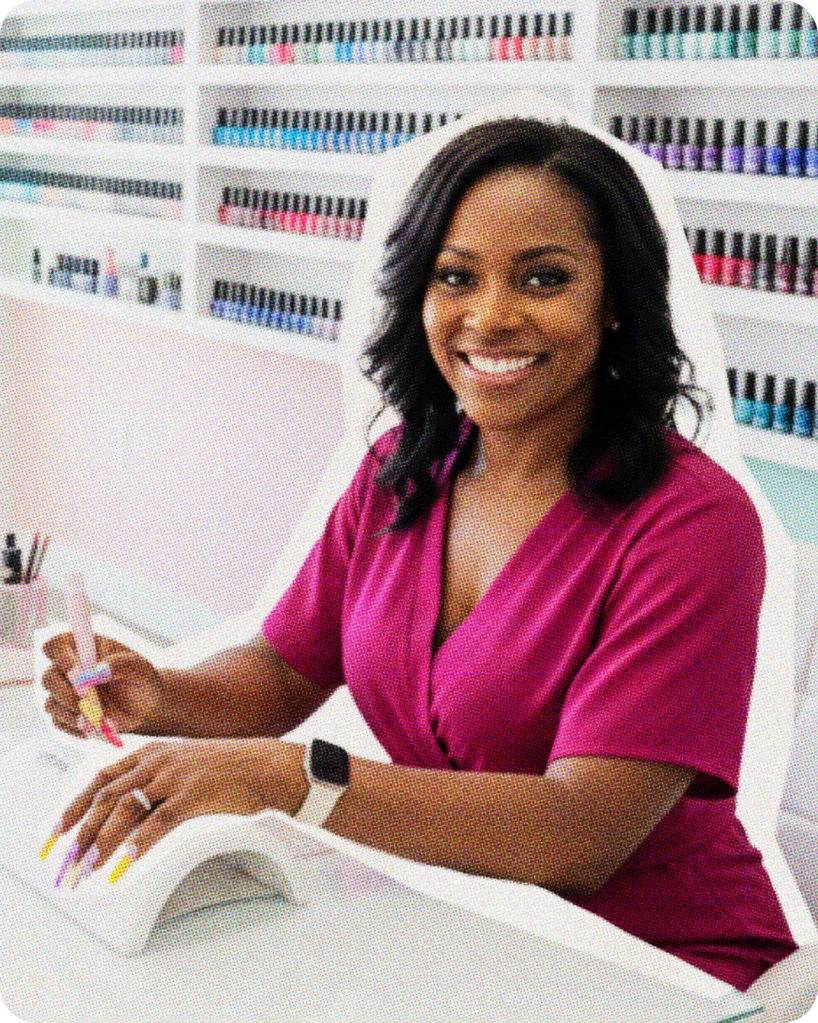 Nail technician sitting in front of a display of nail polish bottles