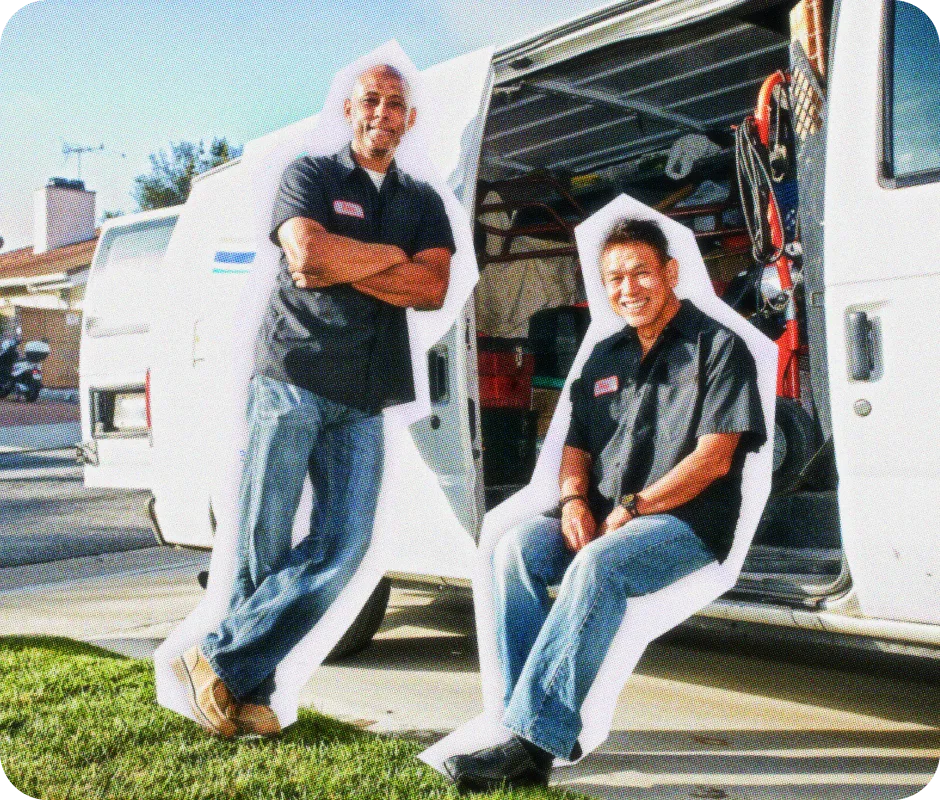 Two plumbers sitting next to their truck.